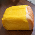 Loaf of bread wrapped in yellow paper on a wooden surface
