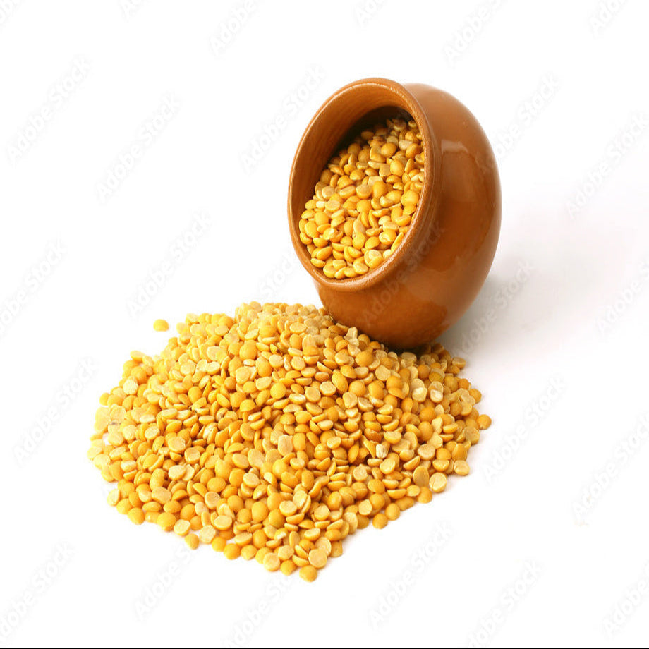 Yellow lentils spilling out of a terracotta pot on a white background